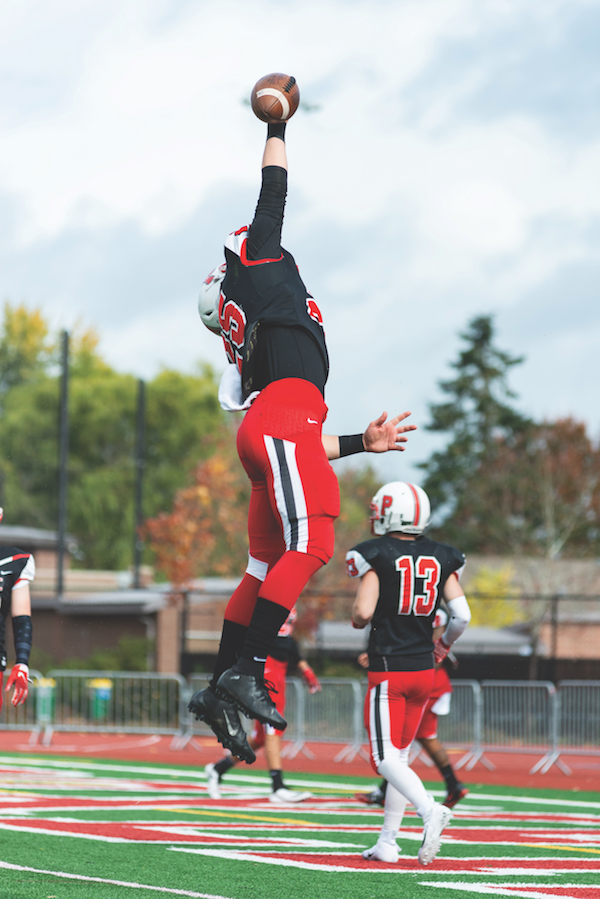Pacific football player reaches to catch a football