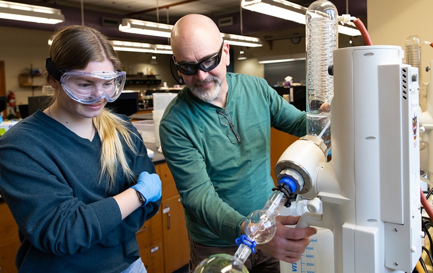 Student And Professor Working Together In Chemistry Lab