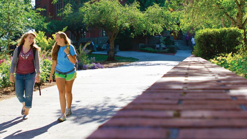 two students walking on the sidewalk on campus