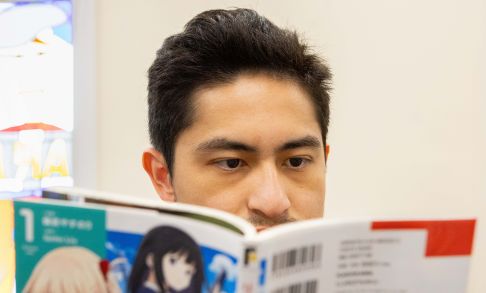 A Pacific student reads manga closely. 
