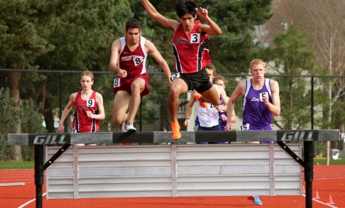 A Pacific track and field athlete leads a pack of steeplechase racers at a competition.