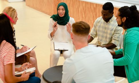 A group of people sit around a table discussing a subject.