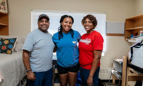 A student poses with their guardians while moving into the dorms during orientation.