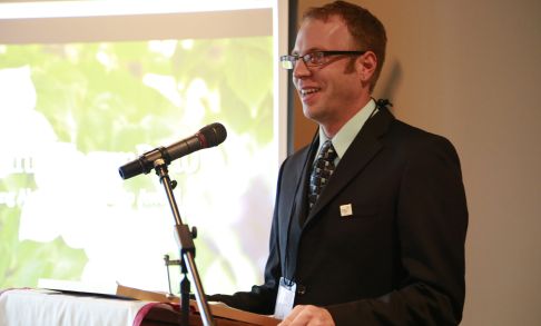 Alex Winn stands at a podium during the 校友 Awards ceremony