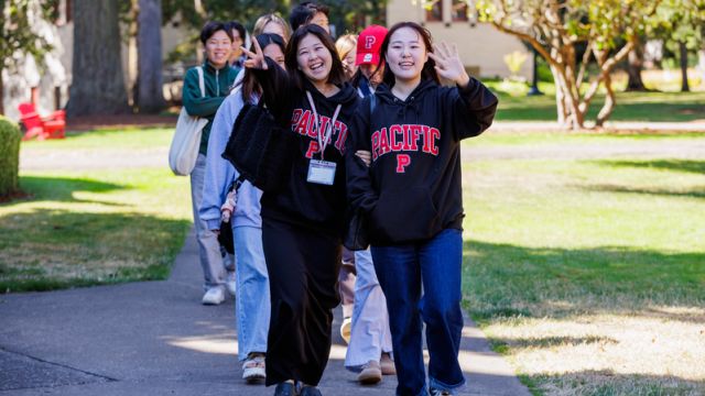 Students in Pacific sweatshirts lead future students around campus