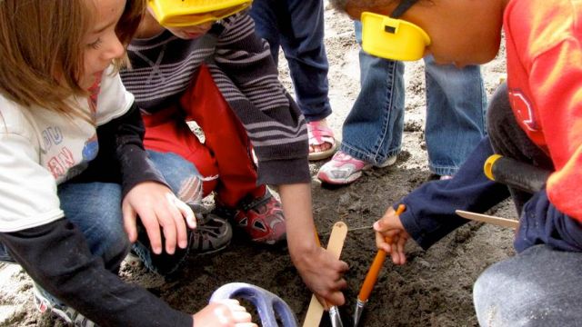 young students digging at the beach