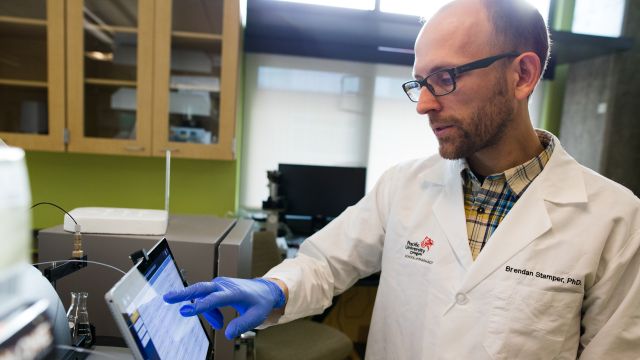Man in lab coat looking at digital screen