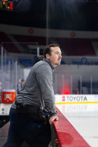 Tomm Orr leans on the side of the bench during pregame warmups.